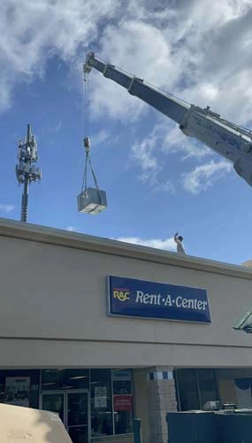 A commercial ac unite being lifted by a crane