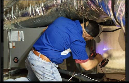 Technician replacing AC ductwork in an attic
