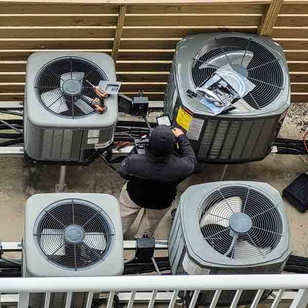Multiple HVAC units outside with a man repairing them