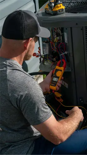 Outdoor central air conditioning unit being serviced beside a home
