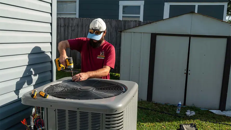 A man working on the top of an outdoor HVAC system
